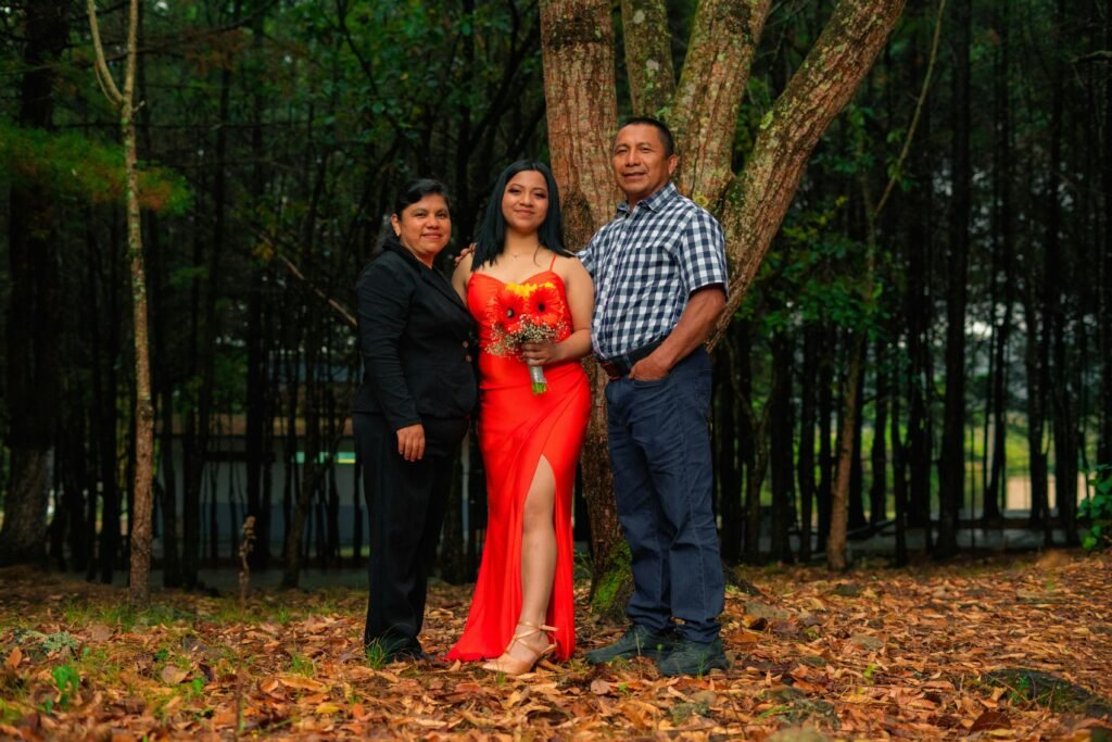 A family poses together in a colorful forest with the focus on a woman in a red dress.